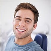 Young man in blue shirt smiling in dental chair