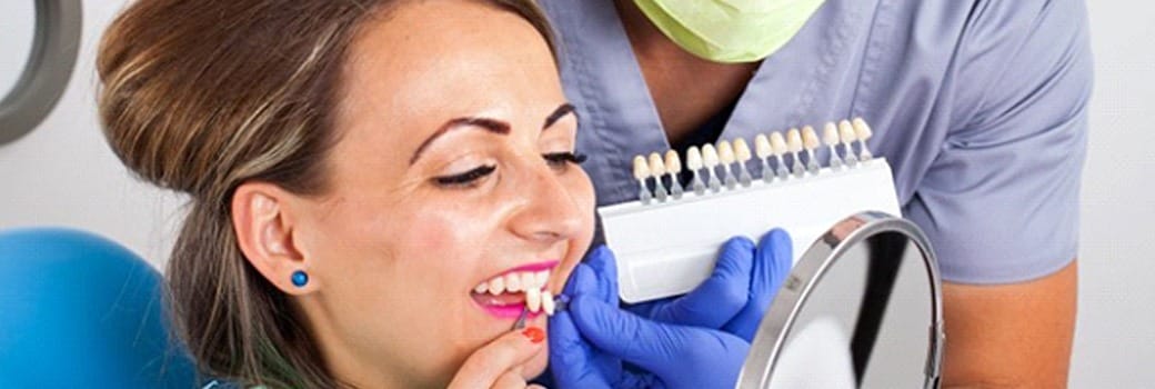 woman holding veneers up to her smile 