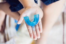 Outstretched hand holding mouthguard for preventing dental emergencies in Greensboro