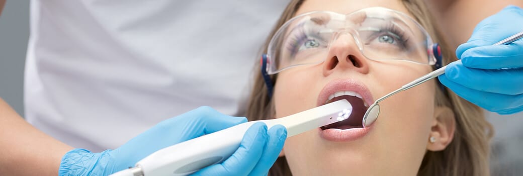 dentist using intraoral camera in woman's mouth