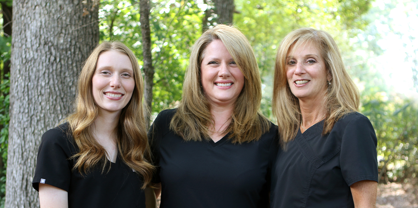 Greensboro dentist and dental team members smiling outdoors