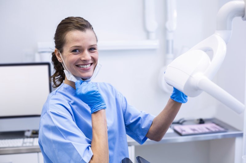 Smiling dental assistant adjusting light