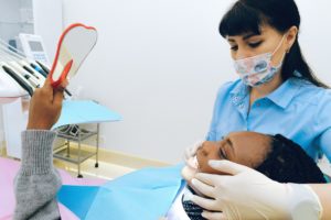 Woman in dentist’s chair looking in mirror