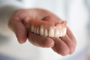 Upper full denture in palm of hand